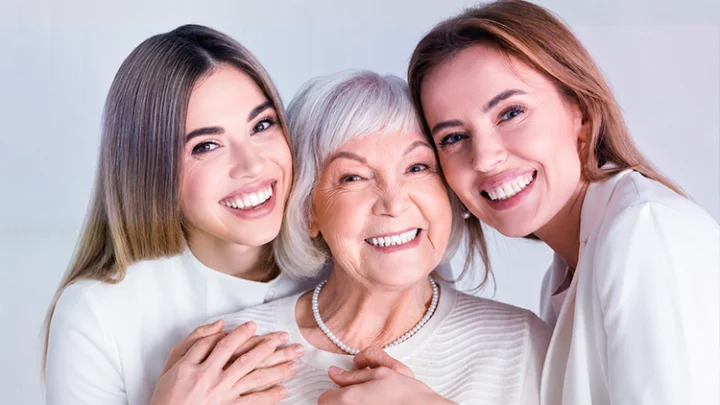 Three smiling women of different generations embracing